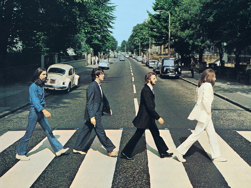 The Beatles walking across the Abbey Road crosswalk in London.